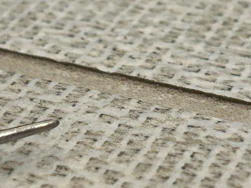 The close-up shows an exposed tile edge at a recessed grout joint.